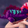 A purple stuffed animal sitting on top of someone 's hand.