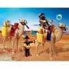 A group of people riding on the backs of camel.