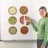 A woman is holding a piece of paper and pointing to six different pizzas.
