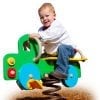 A young boy riding on the back of a green truck.