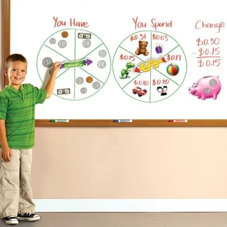 A young boy is standing in front of a board with money and coins on it.
